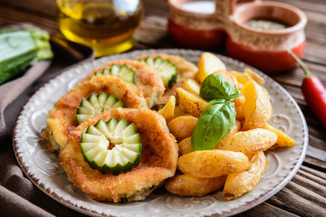 Fototapeta na wymiar Breaded fried zucchini with American potatoes and cucumber