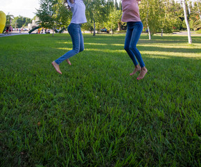 Fototapeta na wymiar Two teen girl friends jumping on grass