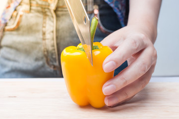 woman hand hold sliced bell pepper Yellow on wooden board