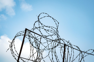 A Fence With Barbed Wire On A Background Of Blue Sky With Vignette