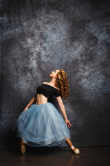 Fototapeta na wymiar beautiful and delicate ballerina in a studio on gray background