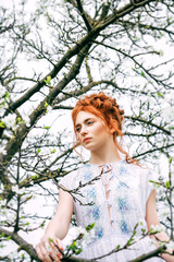 Fototapeta na wymiar Portrait of a beautiful redhead girl in the spring garden