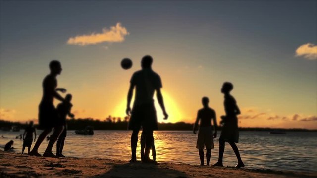 Silhouettes of Brazilians playing altinho beach football at sunset on a tropical beach in Bahia, Nordeste, Brazil