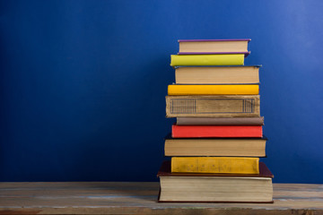 Books on grunge wooden table desk shelf in library. Back to school background with copy space for your ad text. Old hardback books with no labels, blank spine