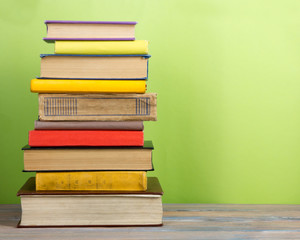 Books on grunge wooden table desk shelf in library. Back to school background with copy space for your ad text. Old hardback books with no labels, blank spine