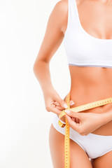 Photo of half of slim woman measuring her waist