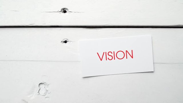 Vision, the word written in red on a card, is dropped on an aged white table. Footage from a series about business related concepts.