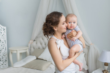 Young mother holds her infant on hands and look at him