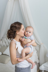 Young mother holds her little baby on hands at home