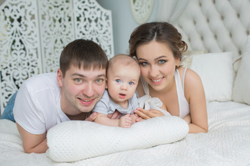 Fototapeta na wymiar Portrait of young family lie on a bed with their little baby