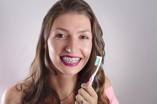 Happy girl with braces holding toothbrush, closeup