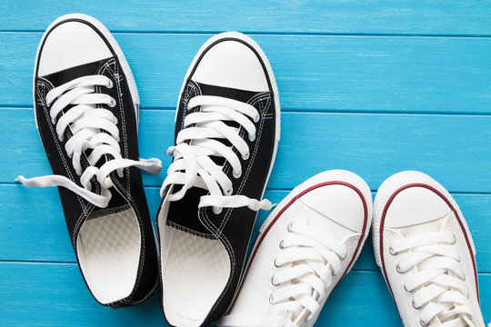 Two pairs of canvas shoes on a blue wooden