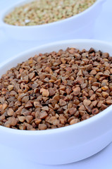 Bowls with buckwheat on background
