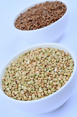 Bowls with buckwheat on background