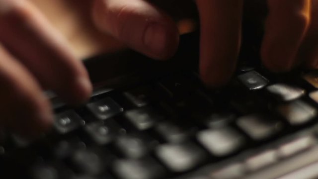 Desktop Keyboard Typing Upper View. The camera trucks along a close up of fingers typing on a black computer keyboard.