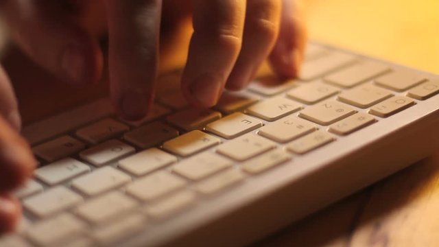 White Keyboard Typing Upper View. The camera trucks along a close up of fingers typing on a white computer keyboard.