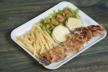 Fast food: kebabs, fries and fresh salad in the tray on the table. 