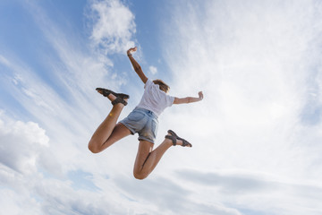 Beautiful and happy girl jumps in the sky