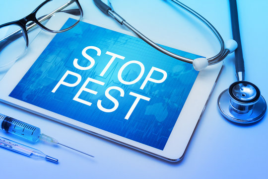 Stop pest word on tablet screen with medical equipment on background