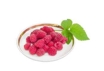 Berries of red raspberry and one raspberry leaf on saucer