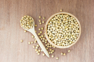 Soybeans on wooden spoon and in a bowl on wooden background,Top view
