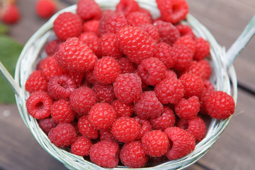 Red fresh raspberries basket on brown rustic wood background