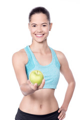 Smiling fit lady offering you fresh green apple