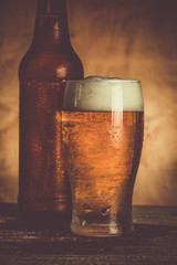 Beer in bottle and glass with ice drops