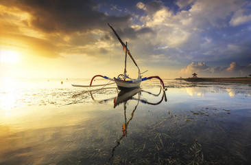 Traditional jukung at Sanur Beach, Bali, Indonesia on sunrise with dramatic sky