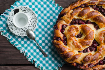 Homemade pie with cherries on wooden table in rustic style.