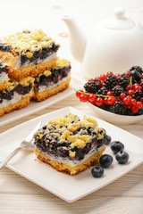 Piece of biscuit cake with blueberries. On white wooden table.