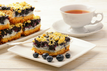 Piece of biscuit cake with blueberries. On white wooden table.