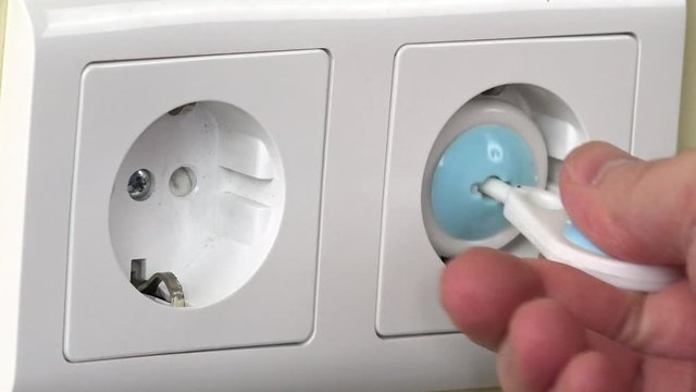 Hand remove safety plugs in electricity socket on wall