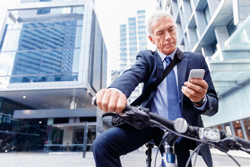 Successful businessman on bicycle with mobile phone
