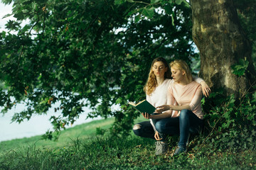 Two young girls read book