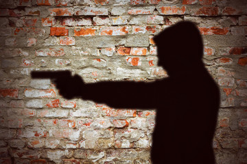 Mann Schatten auf Steinwand zielt mit Pistole