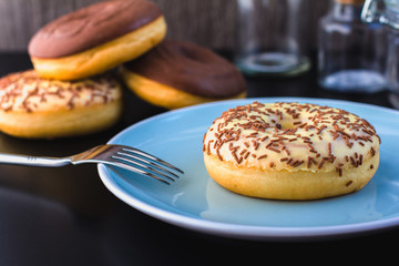 Sweet glazed donut on blue plate. Breakfast serving on table.