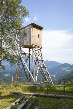 Hunters high tower. Wooden hunters high seat in the mountain forest, against blue sky