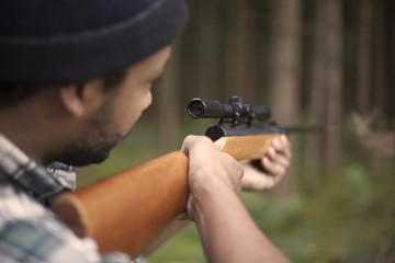 Interracial hunter in the forest aiming at prey