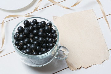 Glass cup full of currant berries and empty paper sheet