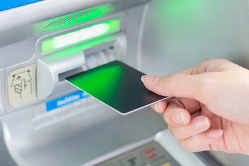 Close up hand inserting card into ATM.