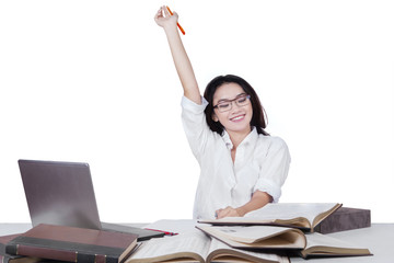 Happy schoolgirl with books raising hand