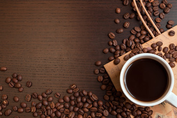 Cup of coffee and coffee beans on dark brown table