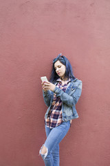 young woman with mobile phone on the wall