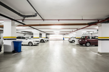 Fototapeta premium Podziemny parking, wnętrze z kilkoma zaparkowanymi samochodami.