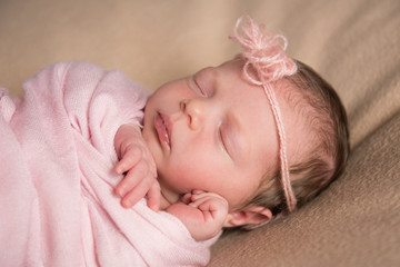 Newborn baby sleeps under a knitted pink cape. Close-up