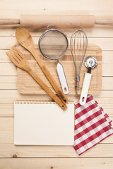 Wooden spoons and other cooking tools with red napkins on the kitchen table.