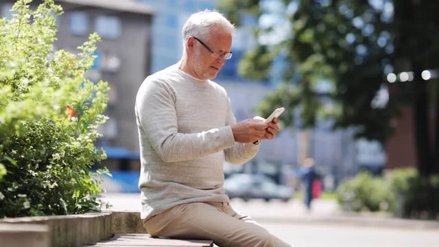 senior man texting message on smartphone in city