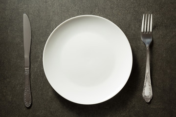 plate, knife and fork on dark background