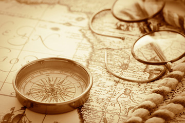 Fototapeta na wymiar antique compass and glasses on vintage map background